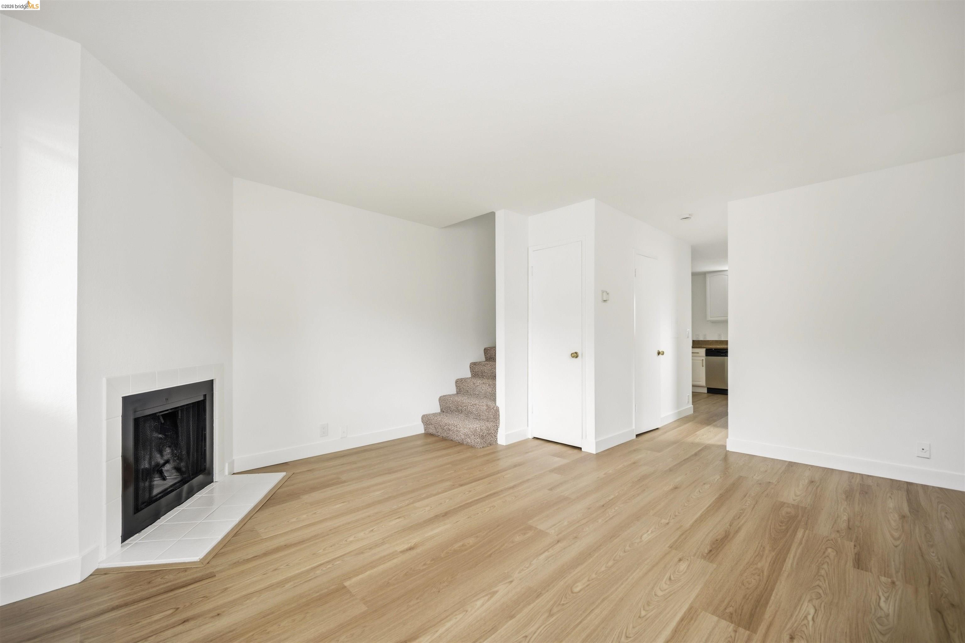 10933 Julius Street, Unit D Oakland, CA 94605 - Photo 3 of 28 Unfurnished living room featuring a tile fireplace and light wood-style floors