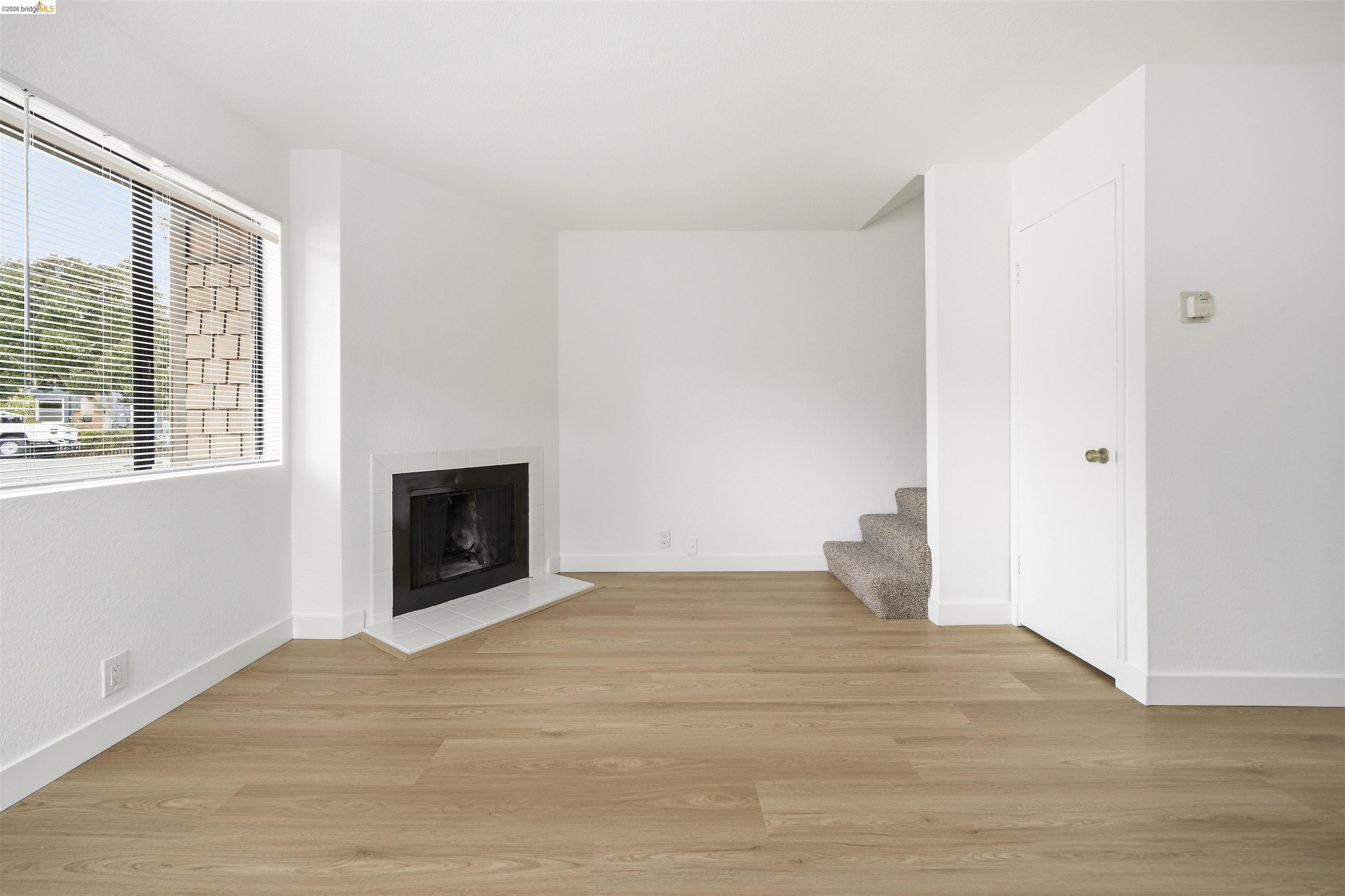 10933 Julius Street, Unit D Oakland, CA 94605 - Photo 5 of 28 Unfurnished living room featuring light wood-style floors and a fireplace with flush hearth