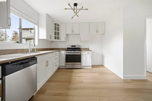 a white kitchen with sink and stainless steel appliances