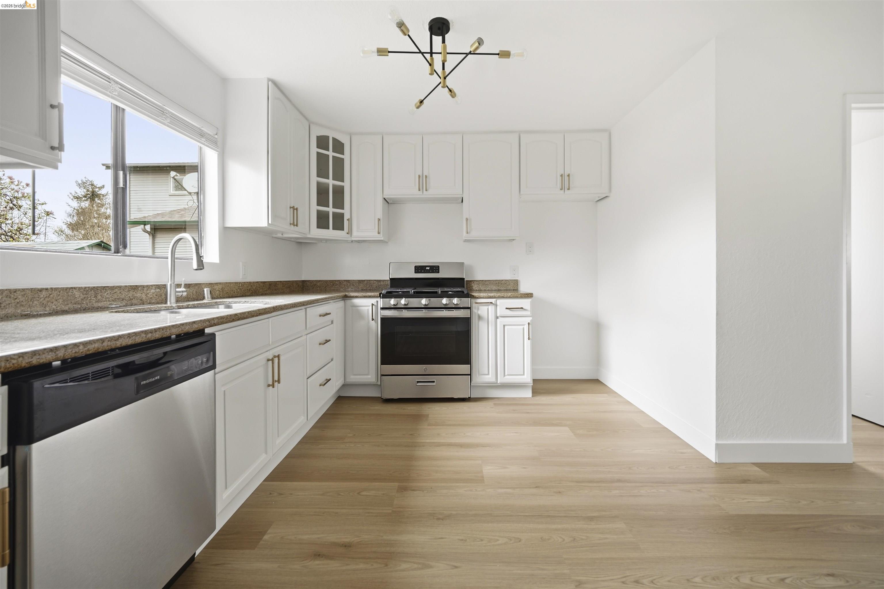10933 Julius Street, Unit D Oakland, CA 94605 - Photo 10 of 28 Kitchen featuring stainless steel appliances, glass insert cabinets, white cabinetry, and light stone counters