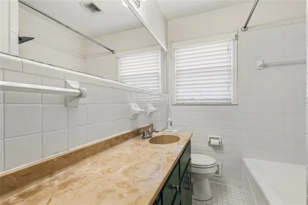 a bathroom with a granite countertop sink a toilet and mirror