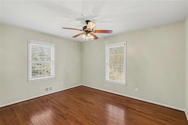 a view of an empty room with chandelier fan and wooden floor