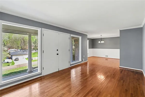 a view of an empty room with wooden floor and a window