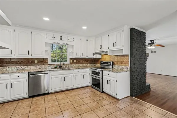 a kitchen with granite countertop white cabinets and white appliances