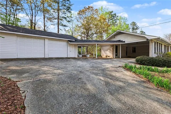 a front view of a house with a garden and trees