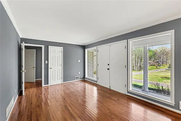 a view of an empty room with wooden floor and a window