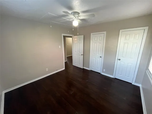 an empty room with wooden floor and fan