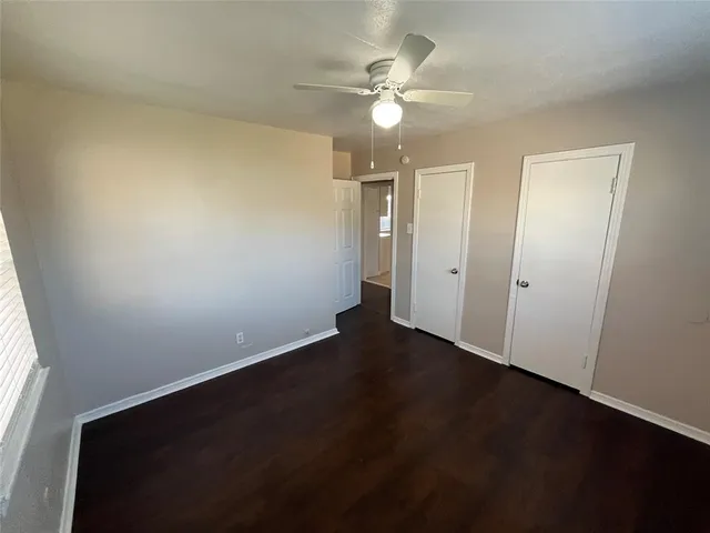 an empty room with a ceiling fan and window