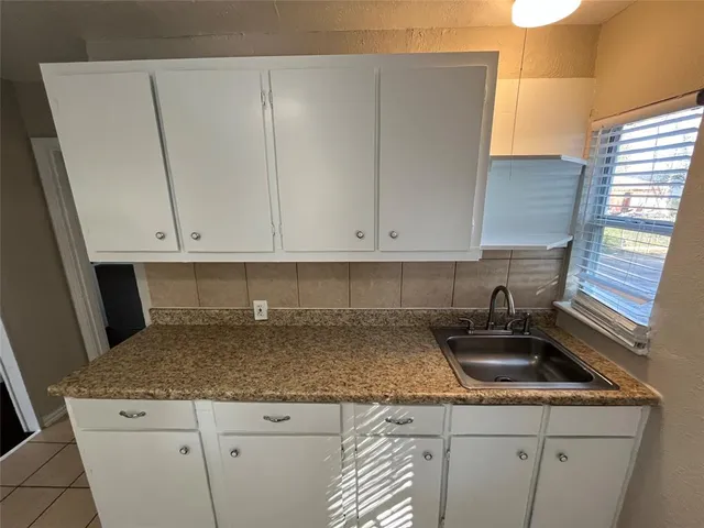 a kitchen with granite countertop white cabinets and a sink