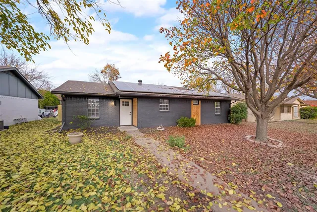 a view of a house with a yard and large tree