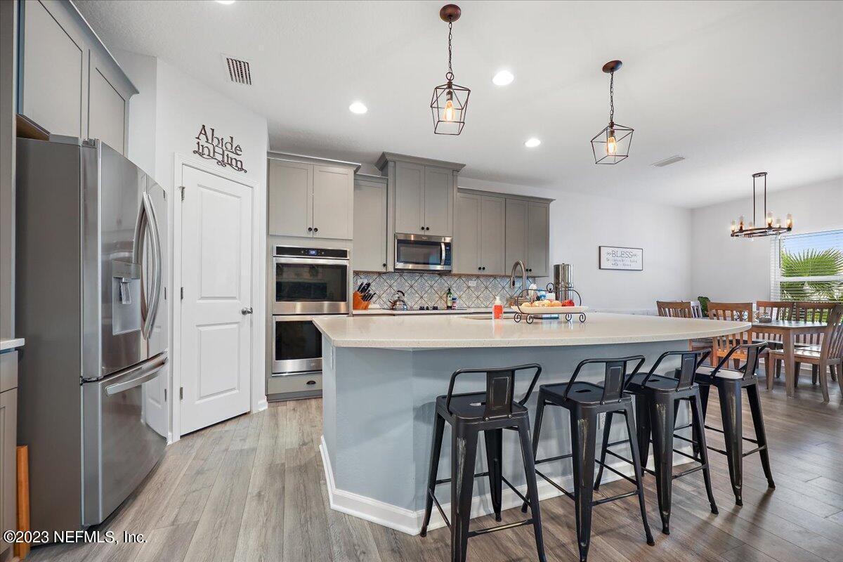 a kitchen with stainless steel appliances a dining table chairs refrigerator and microwave