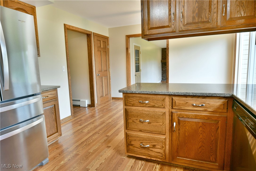 2153 Stillwagon Road Southeast Warren, OH 44484 - Photo 15 of 50 Kitchen with appliances with stainless steel finishes, a baseboard radiator, light wood-type flooring, and brown cabinetry