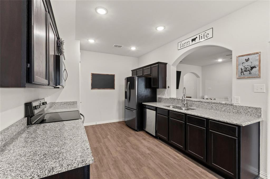 115 Oak Spgs Loop Mabank, TX 75147 - Photo 5 of 15 Kitchen featuring stainless steel appliances, light stone countertops, light wood-style flooring, recessed lighting, and arched walkways