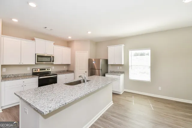 a kitchen with granite countertop kitchen island stainless steel appliances a sink stove and refrigerator