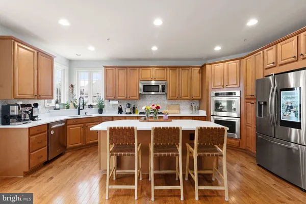 a large kitchen with kitchen island granite countertop wooden cabinets and stainless steel appliances