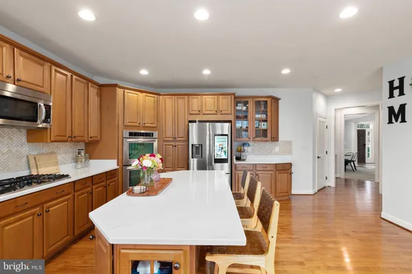a kitchen with stainless steel appliances granite countertop a refrigerator a sink dishwasher a dining table and chairs with wooden floor