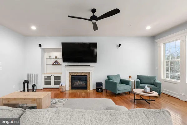 a living room with furniture a fireplace a flat screen tv and windows