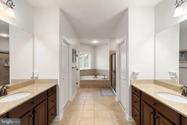 a large bathroom with a granite countertop double vanity sink a bathtub and shower