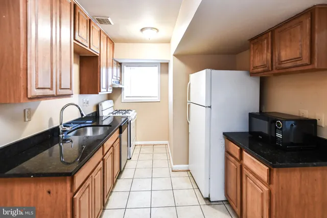 a kitchen with granite countertop a refrigerator a sink and a stove