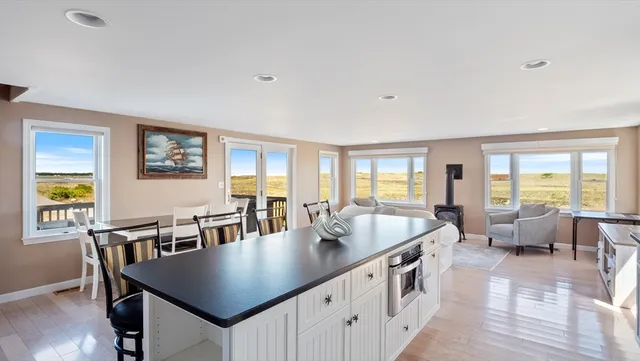 a dining room with stainless steel appliances granite countertop a dining table chairs and a refrigerator a sink with wooden floor