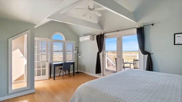 a bedroom with a bed large window with table and chair