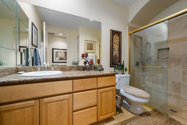 a bathroom with a granite countertop sink toilet a mirror and shower