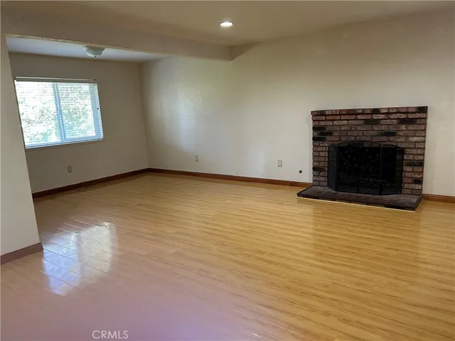 an empty room with wooden floor a fireplace and windows