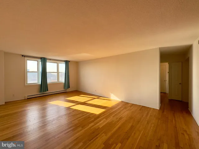 a view of an empty room and wooden floor and window