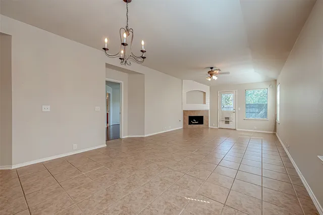 a view of an empty room with a fireplace and chandelier