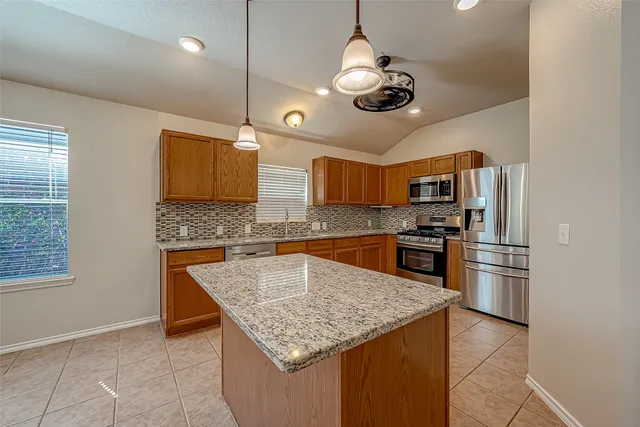 a kitchen with stainless steel appliances granite countertop a sink dishwasher a refrigerator and microwave