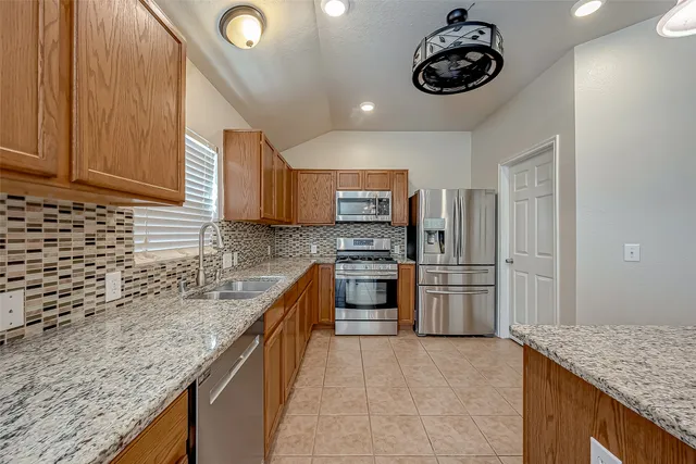 a kitchen with stainless steel appliances granite countertop a sink dishwasher stove top oven and refrigerator