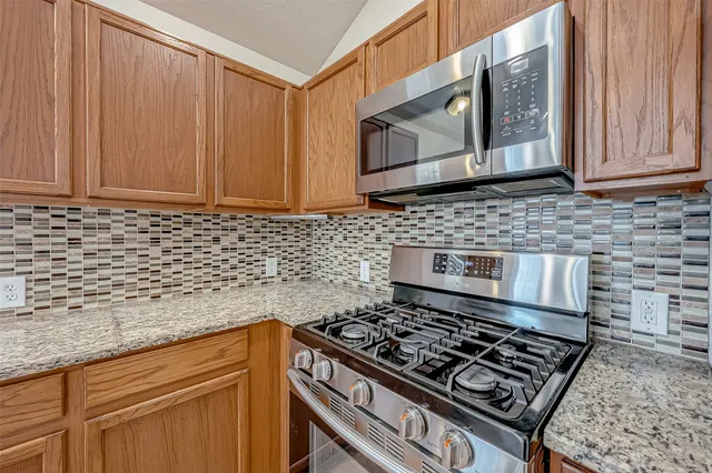 a kitchen with granite countertop a stove sink and cabinets