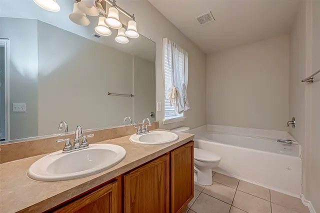 a bathroom with a granite countertop sink a toilet a mirror a bathtub and shower