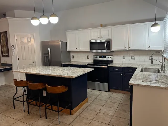 a kitchen with stainless steel appliances granite countertop a sink dishwasher a stove a refrigerator and a dining table with wooden floor