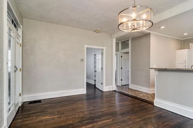 an empty room with wooden floor and hallway