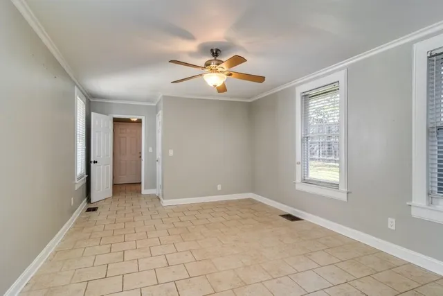 a view of an empty room with window and chandelier fan
