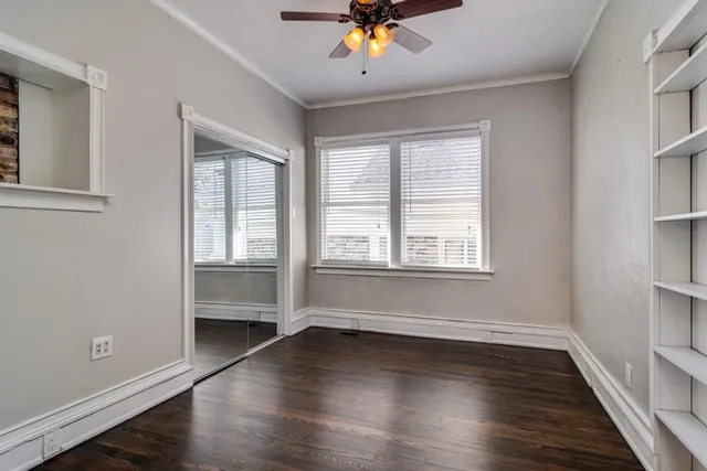 a view of an empty room with a window and wooden floor