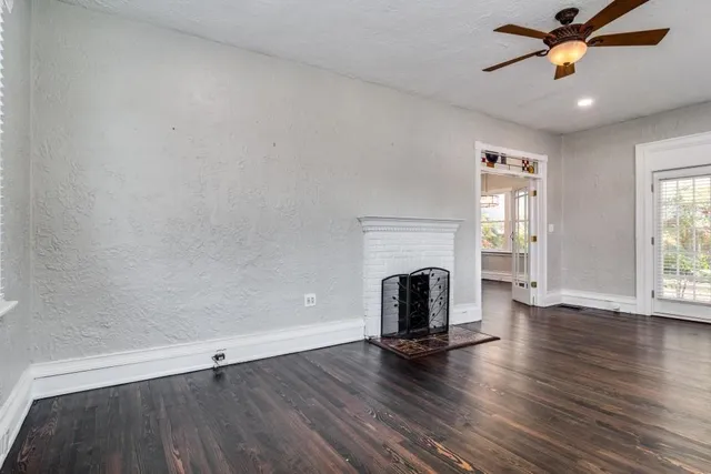 an empty room with wooden floor fireplace and windows