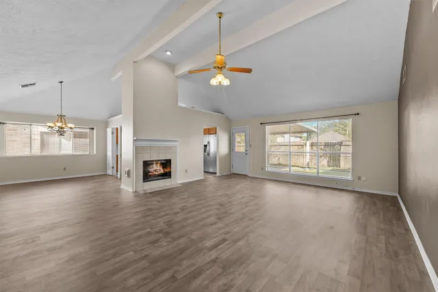 an empty room with wooden floor fireplace and windows