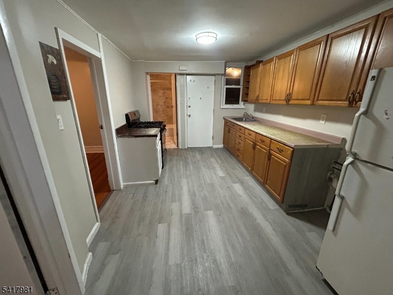 184 Walnut Street Newark, NJ 07105 - Photo 6 of 11 a kitchen with wooden floors and refrigerator