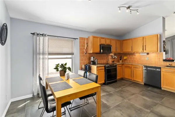 a kitchen with a stove a sink dishwasher a refrigerator with a dining table and chairs