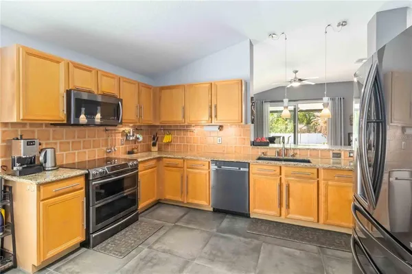 a kitchen with stainless steel appliances granite countertop a stove top oven a sink dishwasher a refrigerator and a microwave