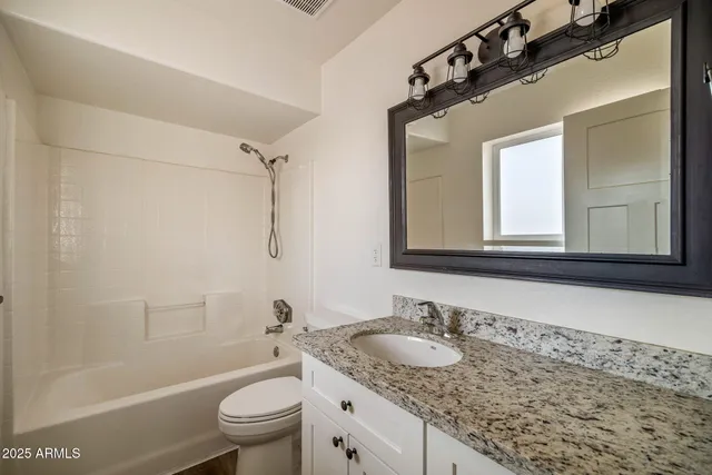 a bathroom with a granite countertop sink toilet mirror and bathtub