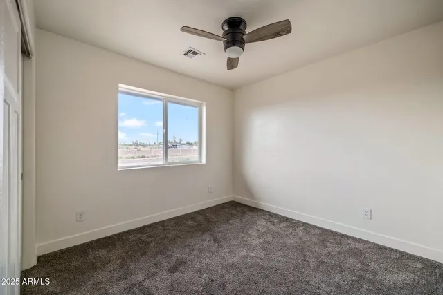 an empty room with a ceiling fan and window