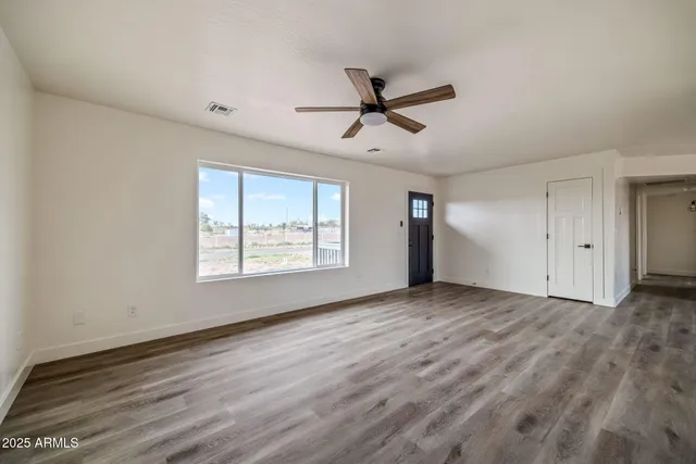 a view of empty room with wooden floor and fan