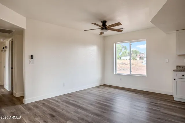 a view of empty room with wooden floor and fan