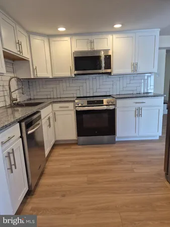 a kitchen with stainless steel appliances granite countertop a stove top oven a sink and a microwave