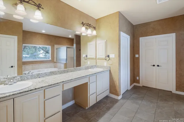 a spacious bathroom with a granite countertop sink a mirror and a bathtub