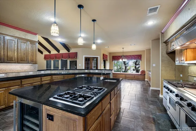 a kitchen with stainless steel appliances granite countertop a sink a stove and a wooden floors