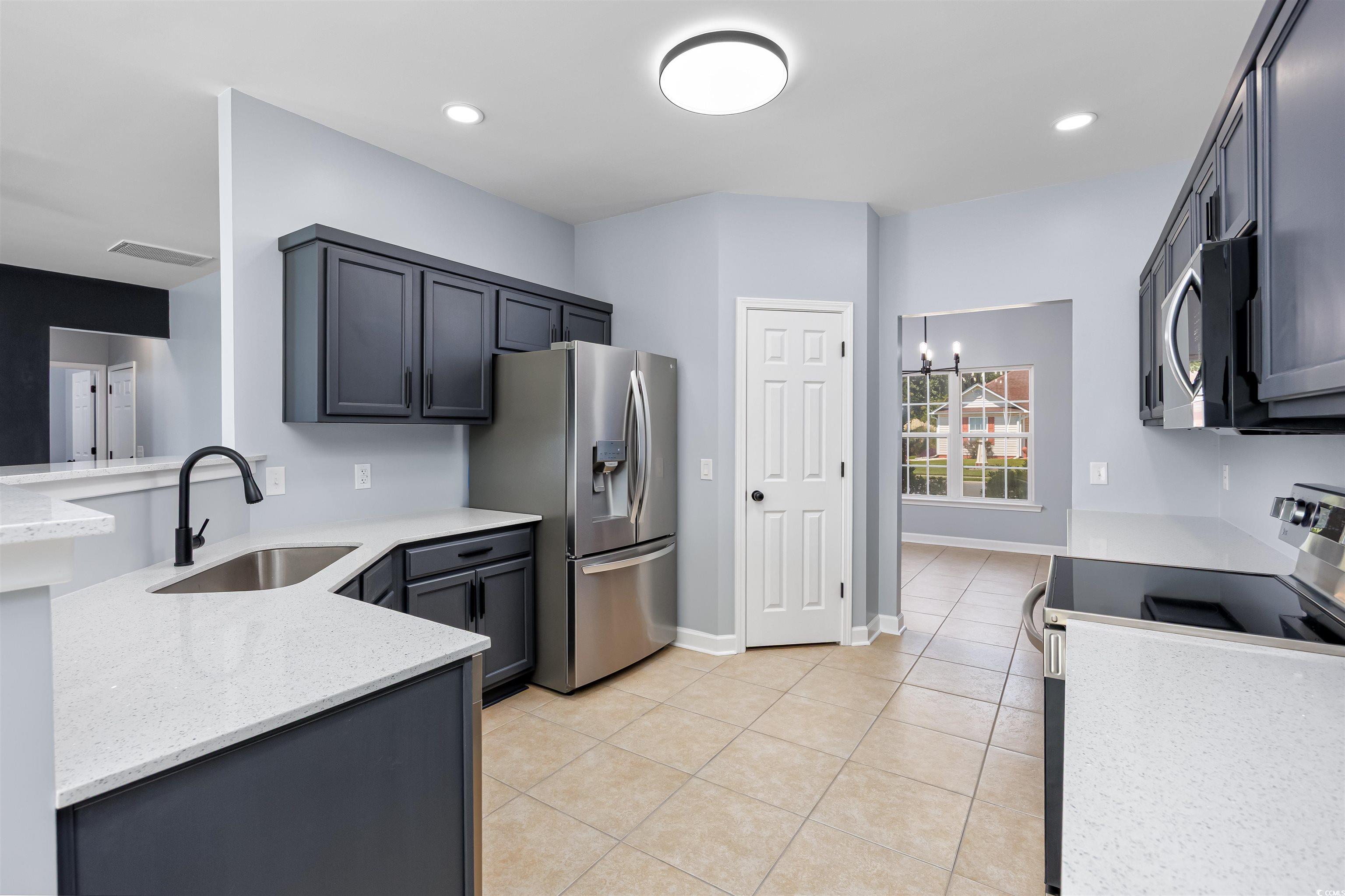 1031 Snowberry Drive Longs, SC 29568 - Photo 11 of 38 Kitchen with stainless steel appliances, light stone countertops, a chandelier, light tile patterned floors, and recessed lighting